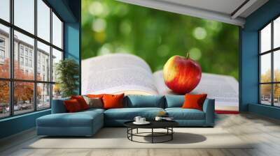 Red apple with open book on green background Wall mural