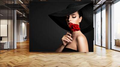 Beautiful Woman and Red Flower, Elegant Lady in Black Wide Broad Brim Hat smelling Rose Wall mural