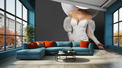 Fashion Woman in Big White Hat hiding Face. Elegant Bride in Mini Dress. Beautiful Lady in Wedding Gown. Stylish Glamour Girl in Sexy Party Dress over Gray Background Wall mural