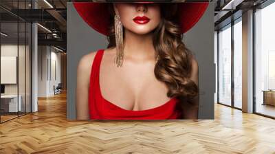 Fashion Woman in Hat hidden Face in Red Decollete Dress with Golden Earring. Elegant Lady in plunging neckline Evening Gown. Sexy Model Portrait with Glossy Red Lips over Gray Studio Background Wall mural