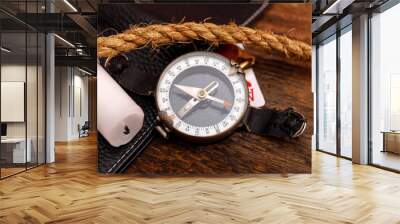 Black leather wallet with old playing card and rope with compass on wooden background. Sailor or soldier set concept. Wall mural