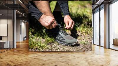 Closeup of attractive young man tying shoelaces before running outdoors Wall mural