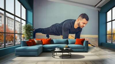 Fitness training athletic sporty man doing plank exercise in gym or home concept. Bearded man exercising workout aerobic at grey background. Wall mural