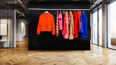 Set of colorful jacket, coat hanging on hanger-black background Wall mural