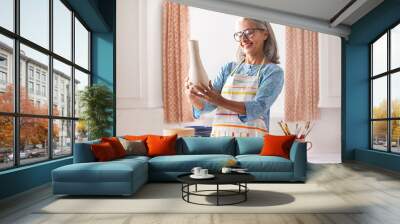 An old woman looking at the vase she is about to paint. Wall mural