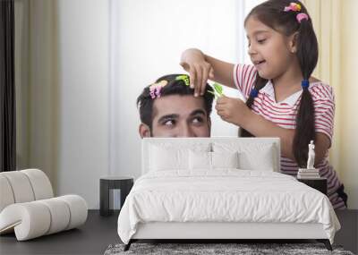 Daughter placing clips in fathers hair and making funny hair style Wall mural