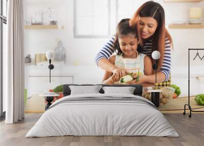 Mother teaching daughter how to peeling cucumber in kitchen
 Wall mural