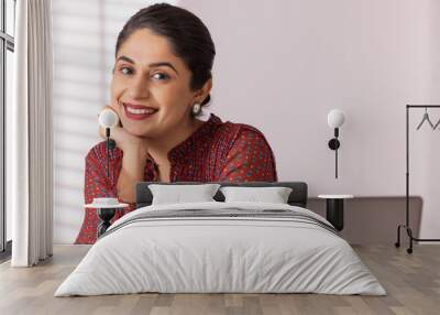 Portrait of a happy working woman with hand on chin Wall mural