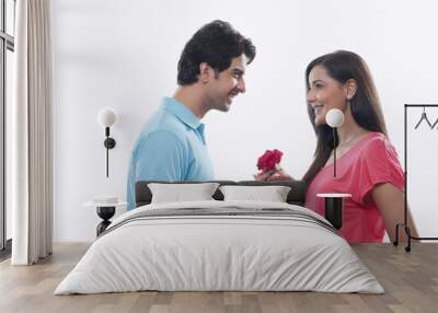 Side view of happy man giving rose to woman over white background Wall mural