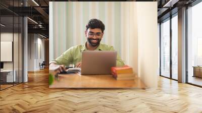 Young man working with laptop in his home office Wall mural