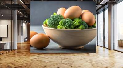 A wooden bowl filled with fresh broccoli florets and brown eggs, with two more eggs resting on the surface beside the bowl. Wall mural