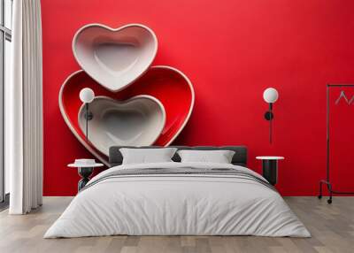 Two white heart-shaped bowls nestled inside a larger red heart-shaped bowl on a bright red background Wall mural