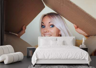 Attractive young girl, looks joyful look inside the unpacked box. Wall mural