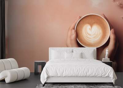 Top view of a female hands in a warm sweater holding mug of delicious cappuccino coffee. Pastel pink background with copy space, banner template.  Wall mural