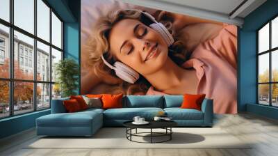 Young beautiful woman smile and listen music while lying on her bed. Happy girl fall asleep listening to relaxing music with headphones. Closeup face portrait.  Wall mural