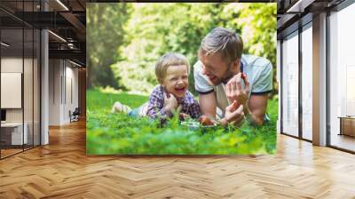 Young father and his son eating strawberries in Park. Picnic. Outdoor portrait Wall mural