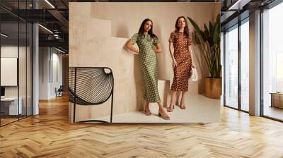 Two fashion model brunette hair wear green  brown dots silk dress sandals  accessory clothes date party walk interior journey summer collection plant flowerpot stairs beautiful woman tan skin friends. Wall mural