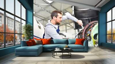 Aircraft mechanic repairs an aircraft engine in an airport hangar Wall mural