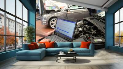 mechanic in a workshop checks and checks the electronics of the car - software update with a modern computer Wall mural