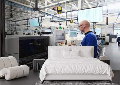 production and assembly of microelectronics in a hi-tech factory - man operates machine in production Wall mural