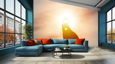 Idea and creativity concept. Silhouette hand holding light bulb with solar energy. New ideas innovation concept. Conceptual solar energy sustainable. Energy savings. Wall mural