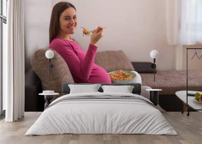 Happy pregnant woman eating vegetables. Wall mural