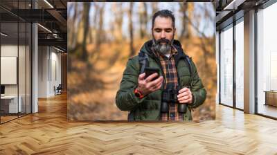 Image of hiker using phone while spending time in nature. Wall mural