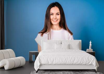 Portrait of excited cute girl in dress holding red present box isolated on blue background Wall mural