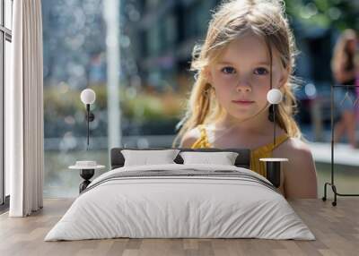 A girl with blond hair and blue eyes in a yellow dress by a fountain, city background Wall mural