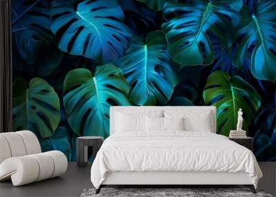 Bright monstera tropical leaves illuminated with blue and green light Wall mural