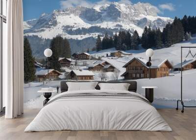 Families enjoy skiing and walking in a snowy landscape beneath charming chalets and majestic mountain peaks in winter wonderland Wall mural