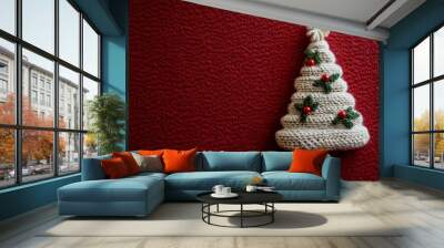 Handmade knitted Christmas tree decoration on a vibrant red background, perfect for holiday festivities and seasonal celebrations Wall mural