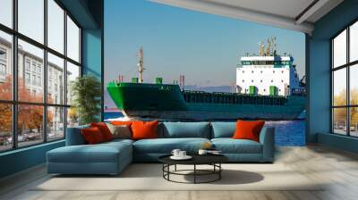 Green cargo ship moving in still water of Baltic sea Wall mural