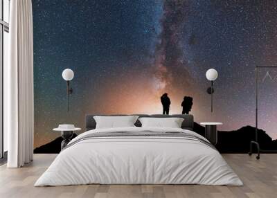 Silhouette of two traveler on the hill in starry night sky.  Bright milky way galaxy behind him.  Wall mural