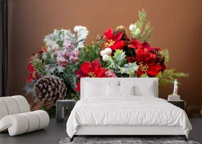 Christmas flower bouquet with red poinsettia, pine cones and spruce branches, festive arrangement on brown background with bokeh lights Wall mural