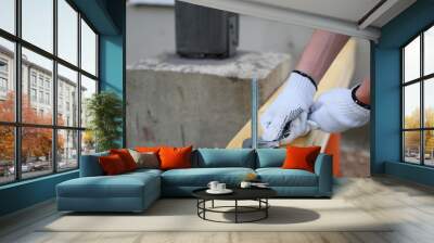 Gloved hand of worker tightens screw nut with adjustable metal wrench in wooden board construction of terrace foundation. DIY concept.
 Wall mural