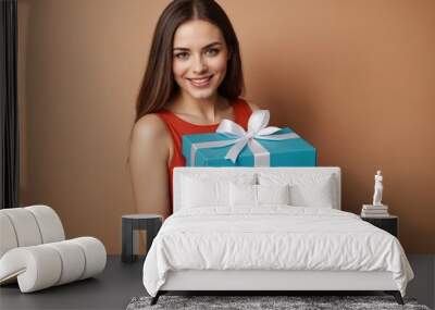 a happy brunette woman holding a gift box.  Wall mural