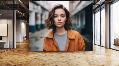 Portrait of a beautiful young woman in an orange jacket on the street Wall mural