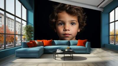 Portrait of a cute little boy with curly hair on a black background Wall mural