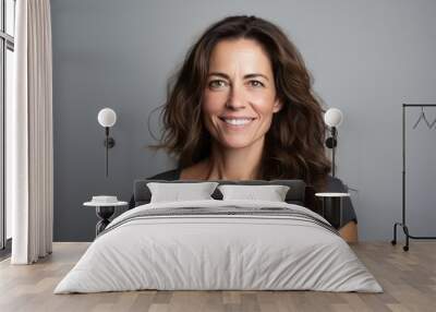 Portrait of a smiling woman with long wavy hair against grey background Wall mural