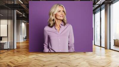 Portrait of beautiful middle aged businesswoman in purple blouse on purple background Wall mural