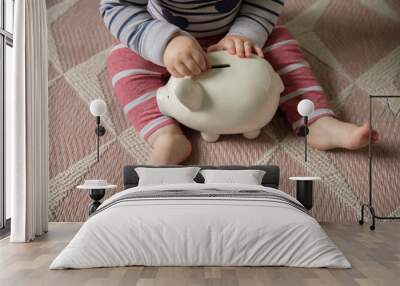 A baby puts money into a piggy bank saving for their future Wall mural