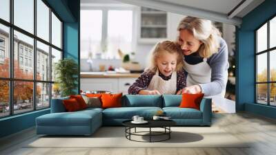 A mother and daughter baking festive christmas cookies together at home during the holidays Wall mural