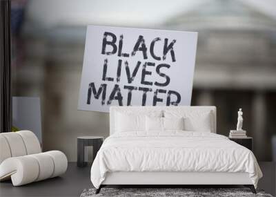 A person holding a black lives matter banner at a protest Wall mural