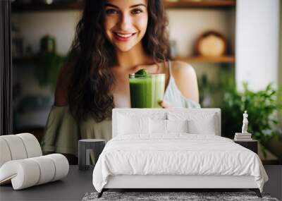 A young woman stood in a kitchen with a healthy green smoothie detox diet drink Wall mural