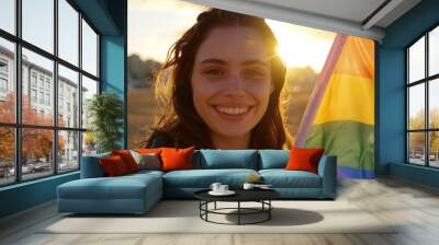 Portrait of a young woman smiling and holding a rainbow LGBTQ pride flag Wall mural