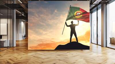 Portugal flag being waved by a man celebrating success at the top of a mountain. 3D Rendering Wall mural