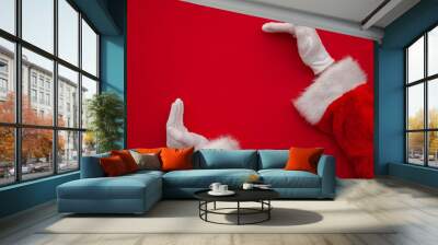 Santa Claus making frame with hand on red background with copy space Wall mural