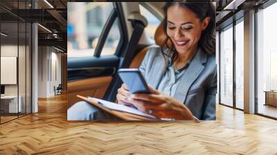 smiling executive woman, using a mobile phone, sitting back seat of the car Wall mural