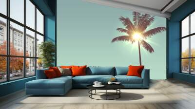 Tropical palm tree silhouette against bright sunlight Wall mural